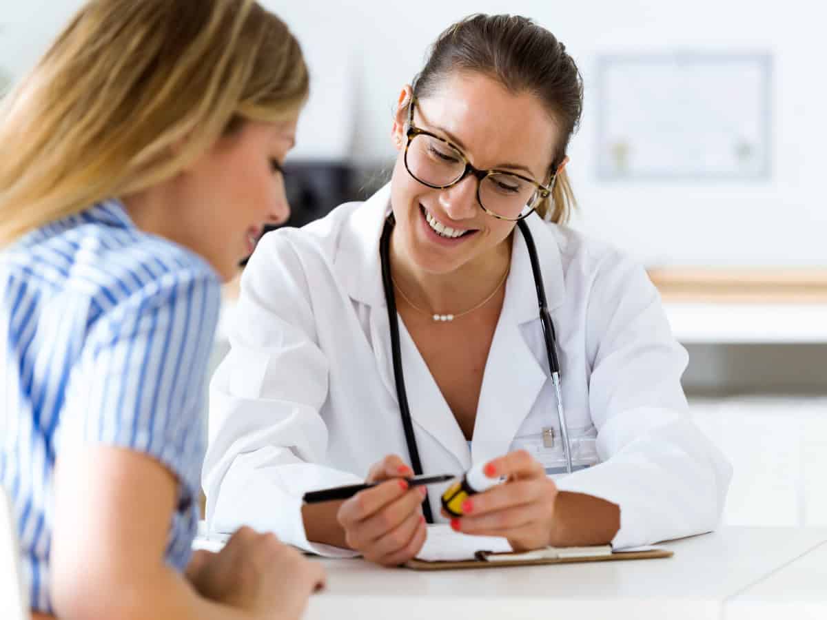 Una médico explica de manera clara la medicación a su paciente cuya adherencia mejora.